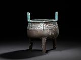 an old bronze pot with a handle sitting on a wooden stand