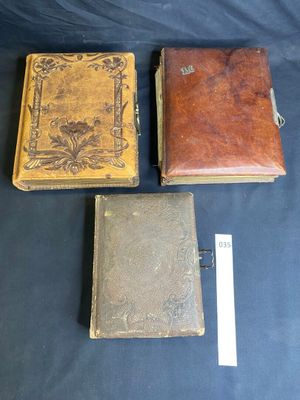 three antique leather bound books are sitting on a blue cloth