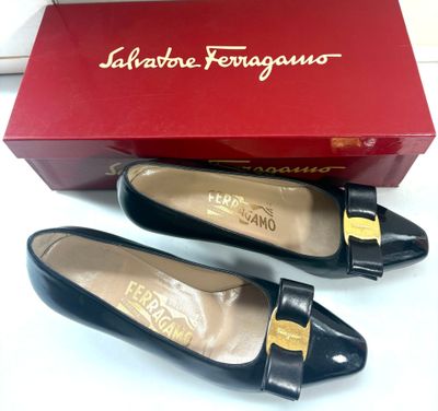 une paire de chaussures noires dans une boîte rouge posée sur une surface blanche