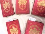 quatre livres rouges ornés de dorures, posés sur une table
