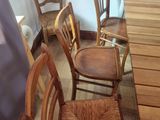 several wooden chairs and a table in a room with a blue curtain