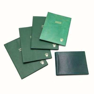 four green passport cases sitting on top of each other on a white surface