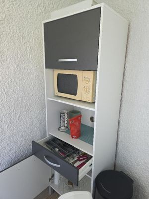 une petite armoire sur laquelle est posé un micro-ondes, à côté des toilettes