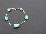 un bracelet en or orné de perles de turquoise et d'une chaîne en or