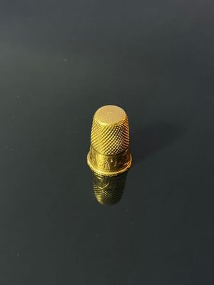 a close up of a gold thimble on a black surface