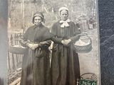 an old photo of two women standing next to each other on a table
