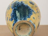 a yellow and blue vase sitting on top of a wooden table