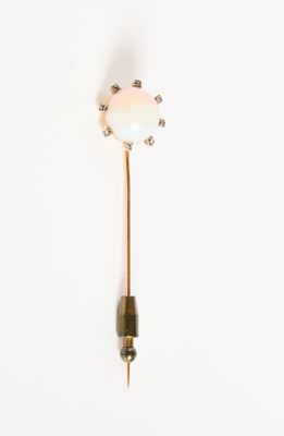 une broche dorée et blanche ornée d'une fleur
