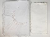 two pieces of white cloth and a pair of scissors on a table
