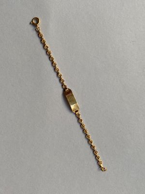 gros plan d'un bracelet en or sur une surface blanche