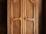 une vieille armoire en bois dans une pièce sombre au sol en parquet
