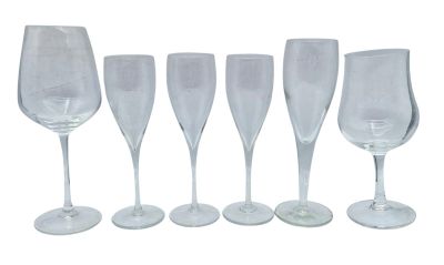 six clear wine glasses lined up in a row on a white surface