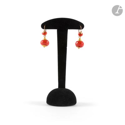 a pair of red and gold earrings on a black stand