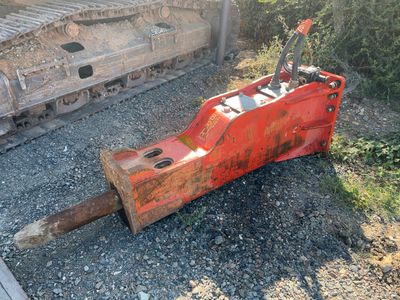 a red bulldozer sitting on the ground next to a pile of rocks