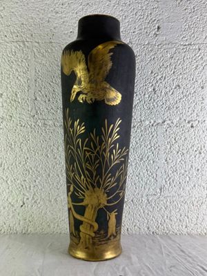 un vase noir et doré posé sur une table blanche