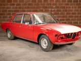 a red car that is parked in front of a brick wall