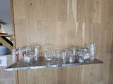 many empty glasses on a metal shelf in a kitchen