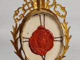 a gold and red wax seal hanging from a gold chain