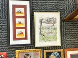 many pictures hanging on the wall above a sink