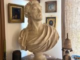 a bust of a man sitting on a table in front of a window