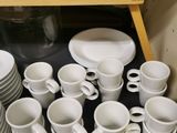 a lot of cups and saucers on the shelf