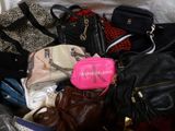 a pile of purses and handbags sitting on a bed