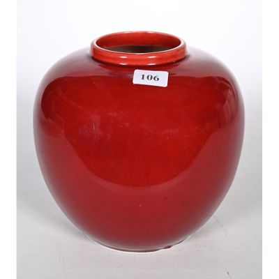 un vase rouge muni d'une étiquette, posé sur une table