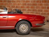 a red convertible car parked in front of a brick wall