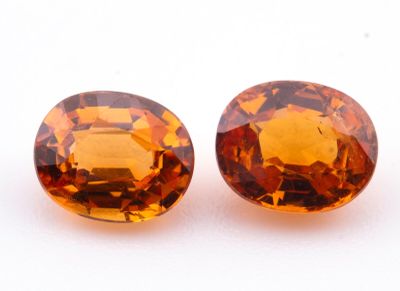 deux saphirs orange taillés en ovale sur un fond blanc