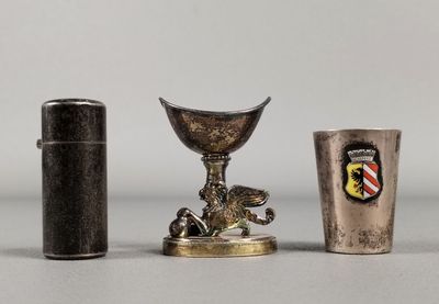 deux tasses en argent et un briquet sont posés sur une table