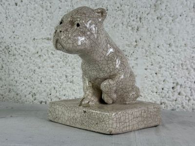 a ceramic sculpture of a dog sitting on top of a block
