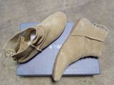 une paire de chaussures en daim beige posée sur une boîte bleue