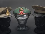 three military hats on a mannequin head on a black background