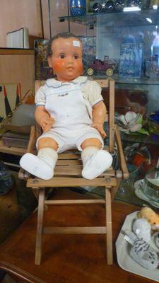 une poupée assise sur une chaise dans une vitrine