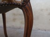 a close up of a wooden chair with a brown and white upholstered seat