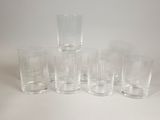 six clear glass tumblers lined up on a white surface