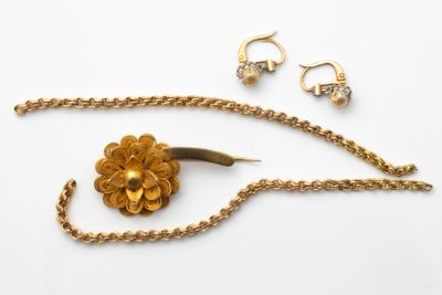 une photo d'un collier en or orné d'une fleur et d'une paire de boucles d'oreilles