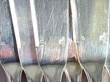 a lot of silver spoons that are hanging on the wall