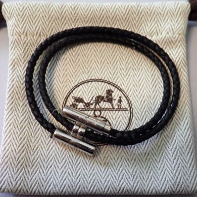 un gros plan sur un bracelet en cuir noir muni d'un fermoir en argent