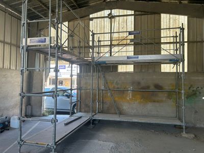 un échafaudage au milieu d'un immeuble, avec une voiture garée à l'arrière-plan