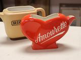 a red heart shaped teapot next to a yellow teapot