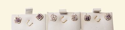 four pairs of earrings hanging from a rack on a wall