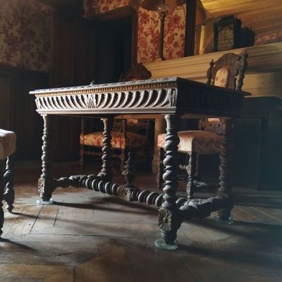 une table et deux chaises dans une pièce avec une cheminée en arrière-plan