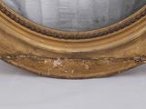 a gold oval mirror sitting on a white surface