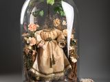 a glass clochet with a doll inside of it