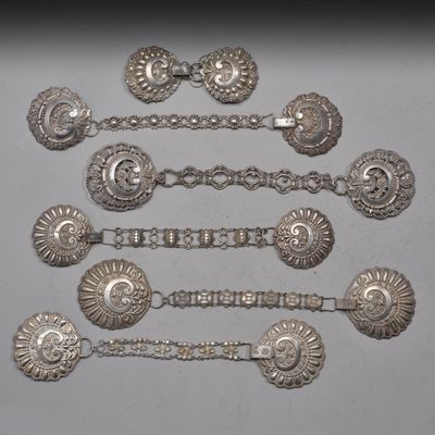 six cuillères en argent et une paire de boucles d'oreilles posées sur une table