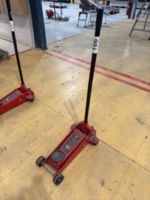 two red jacks sitting on the floor in a garage