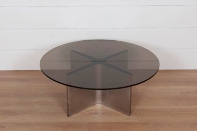une photo d'une table en verre avec un piètement en métal posée sur un parquet