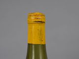 an old bottle of wine with a yellow cap on a gray background
