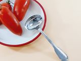 tomatoes on a plate with a spoon and spoon rest on a table